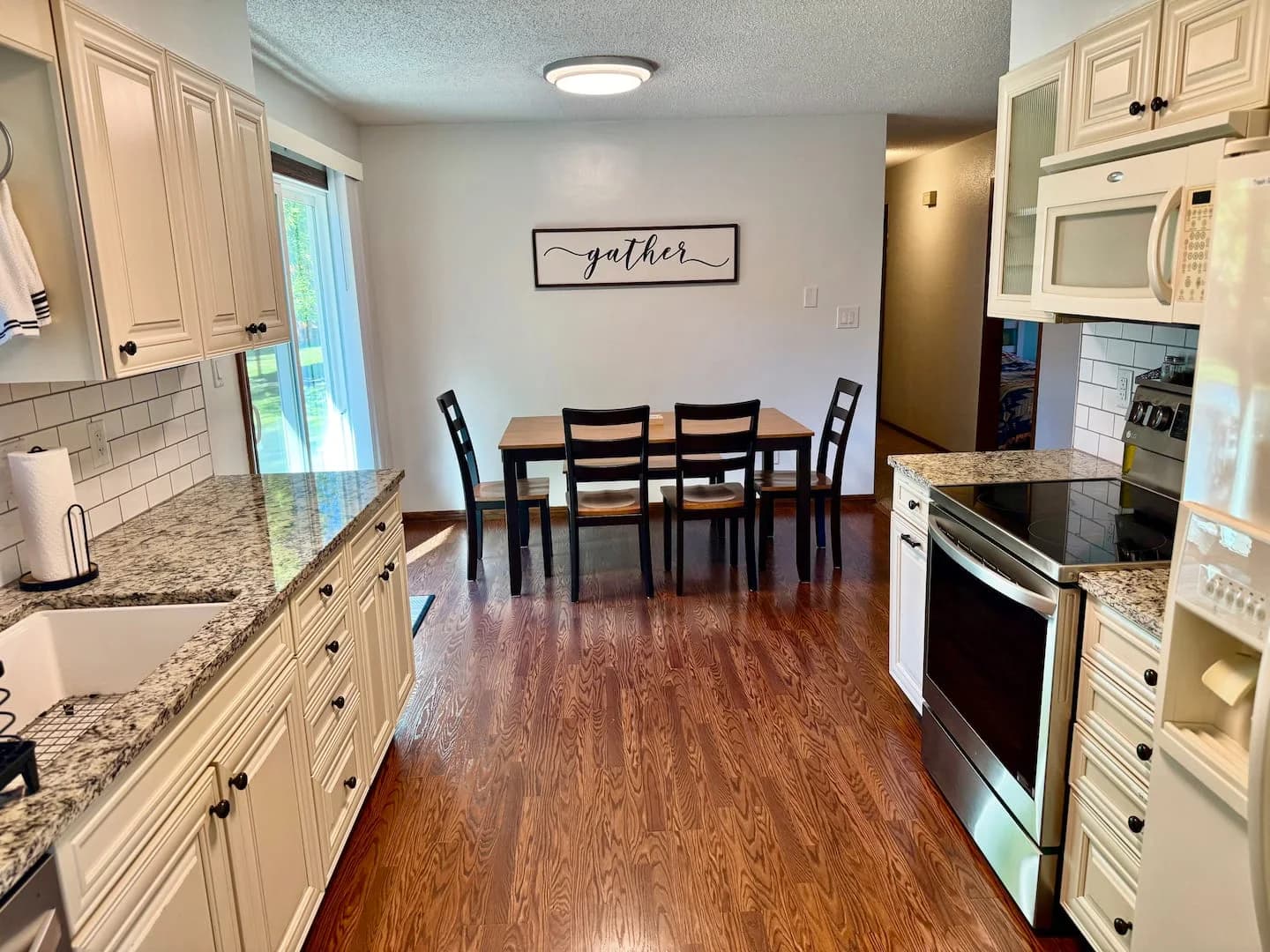 Kitchen counters on either side of an aisle leading to a dining table beneath a framed Gather sign