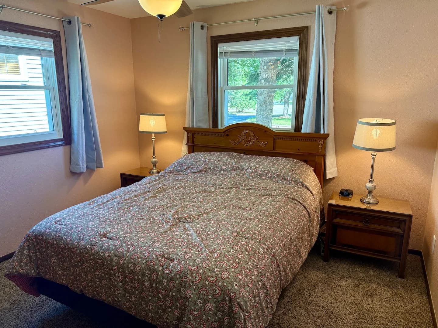 Queen bed with a carved wooden headboard and patterned quilt, flanked by nightstands and lamps